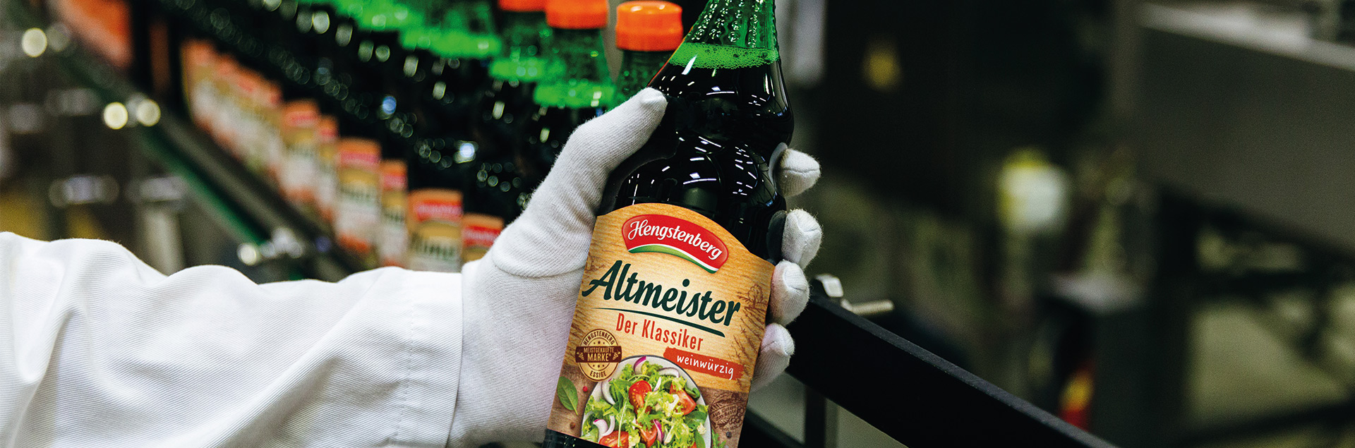 A hand is holding a bottle of Altmeister vinegar.